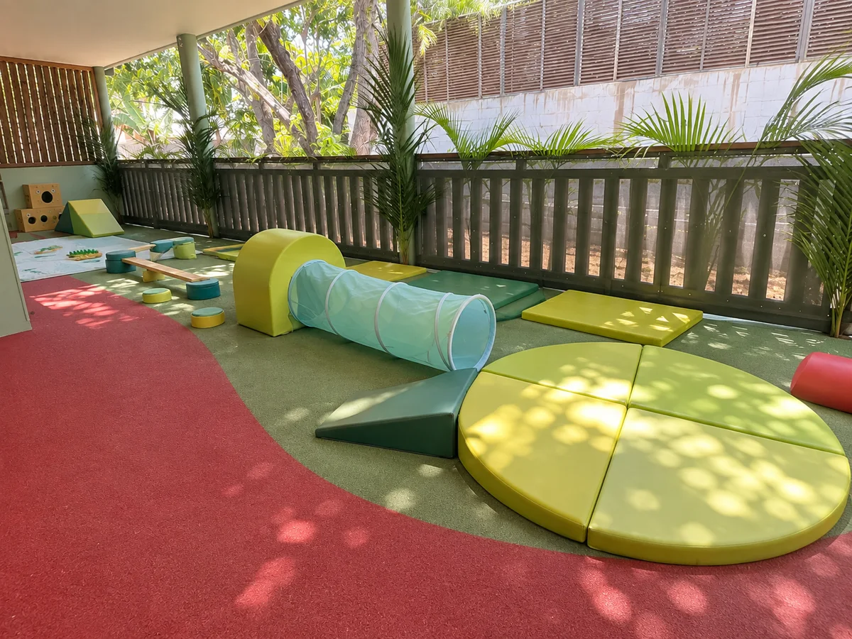 Terrasse couverte de la micro-crèche Bonbon à Saint-Pierre, avec sol souple rouge et vert et modules de motricité