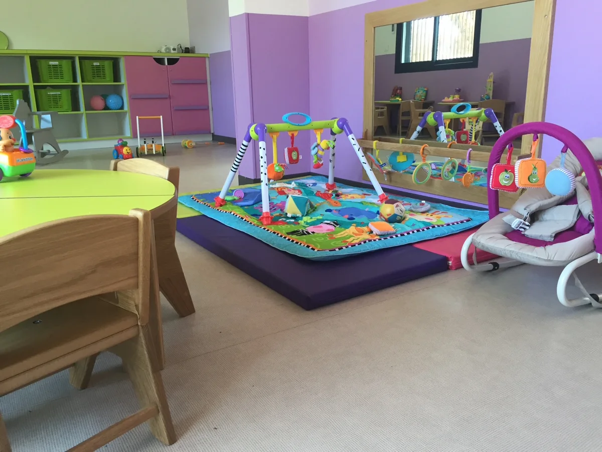 Espace des bébés chez Caramel : tapis d’éveil à arche, transat et grand miroir mural