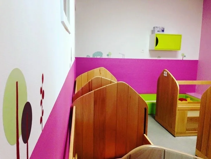 Chambre aux murs fuchsia décorés d’arbres peints, avec des lits en bois à hauteur d’enfant aux Makis
